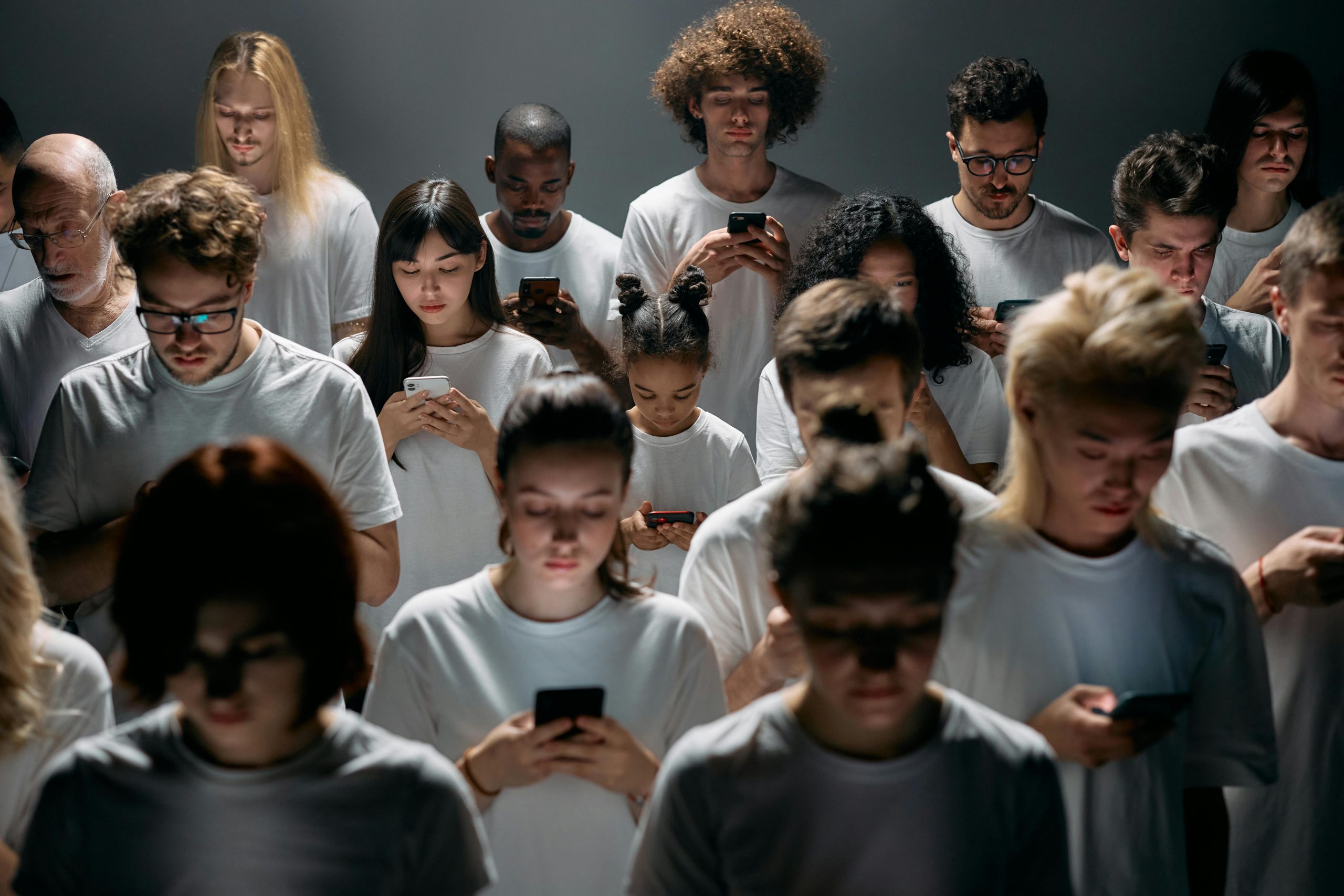 Several people in white t-shirts all focused on phones
